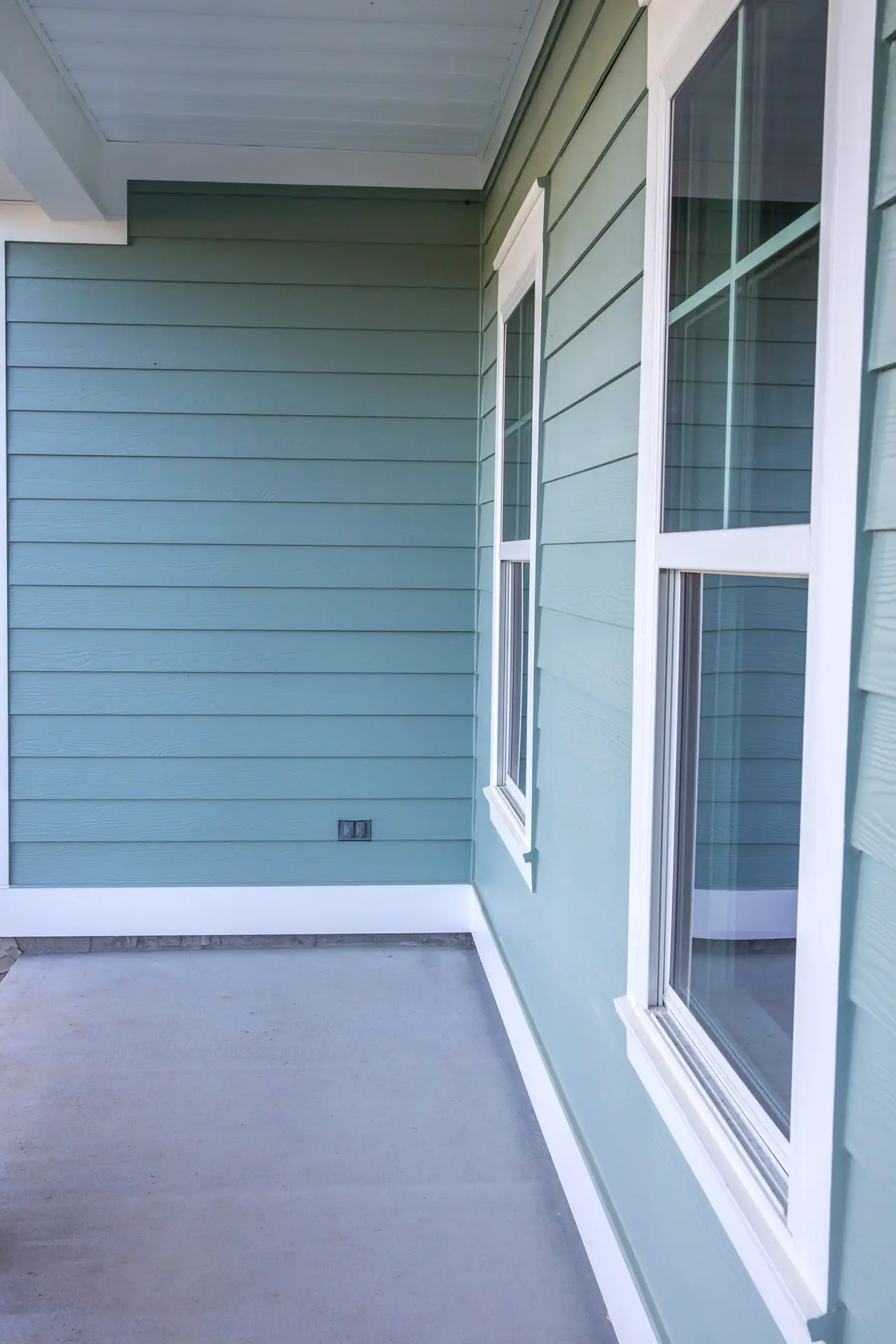 Clean and modern light blue horizontal siding with white window trim and a concrete patio, highlighting professional siding services in Cincinnati, OH.