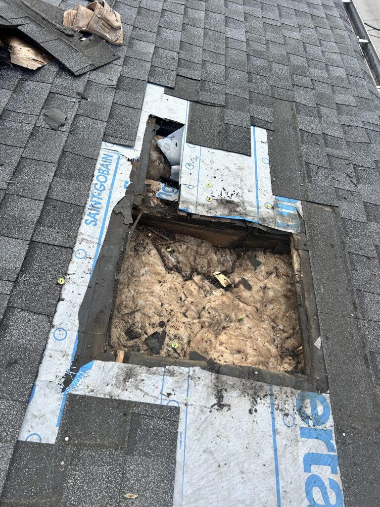 Roofing contractors fixing a hidden leak on a shingled roof.